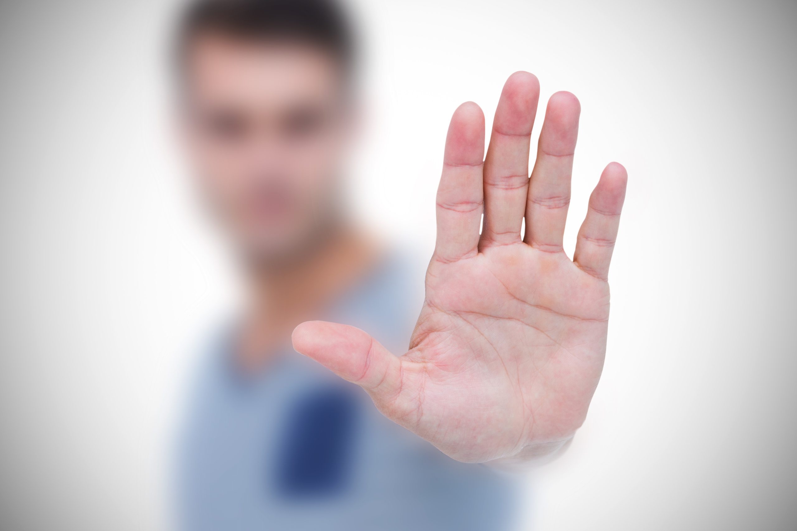 blurry man making stop sign with hand